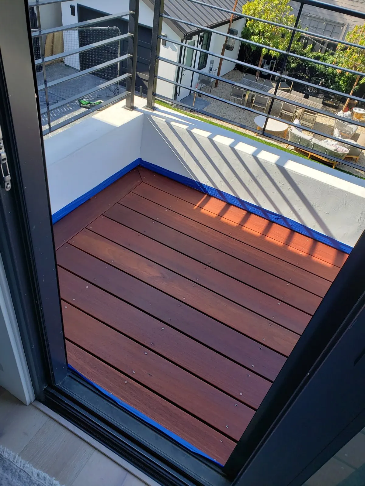 Rich red-brown stained wood deck on a balcony with white walls and navy trim