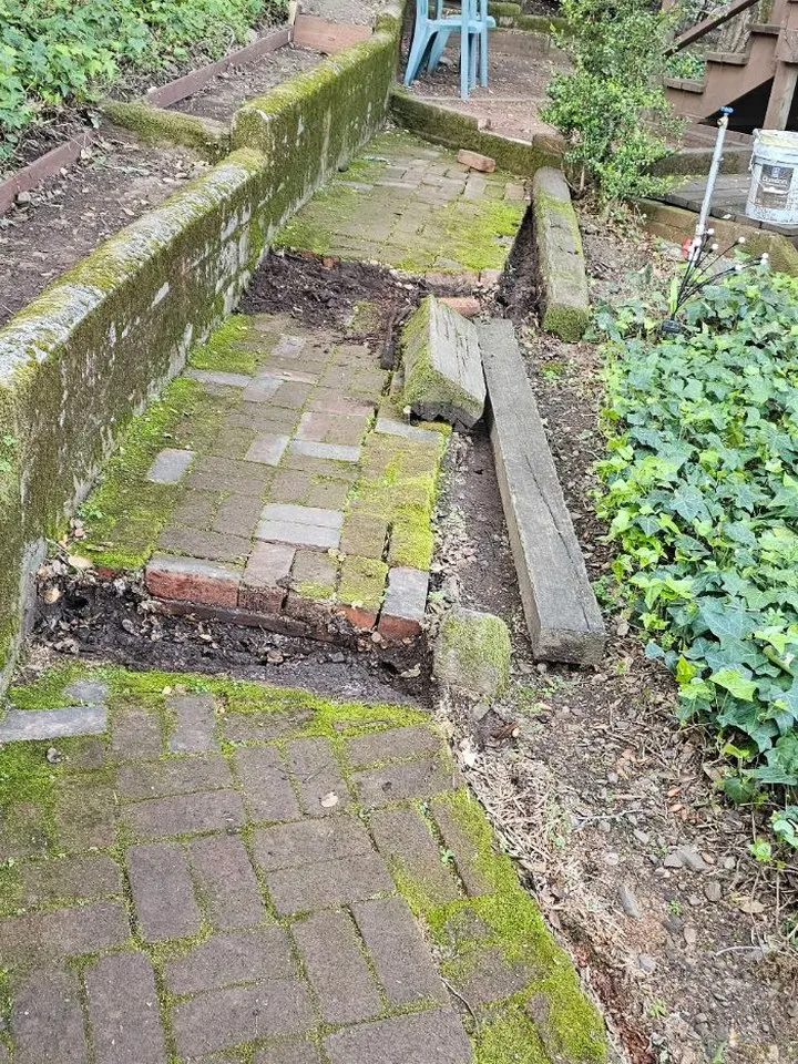 Old mossy brick walkway along a stone wall