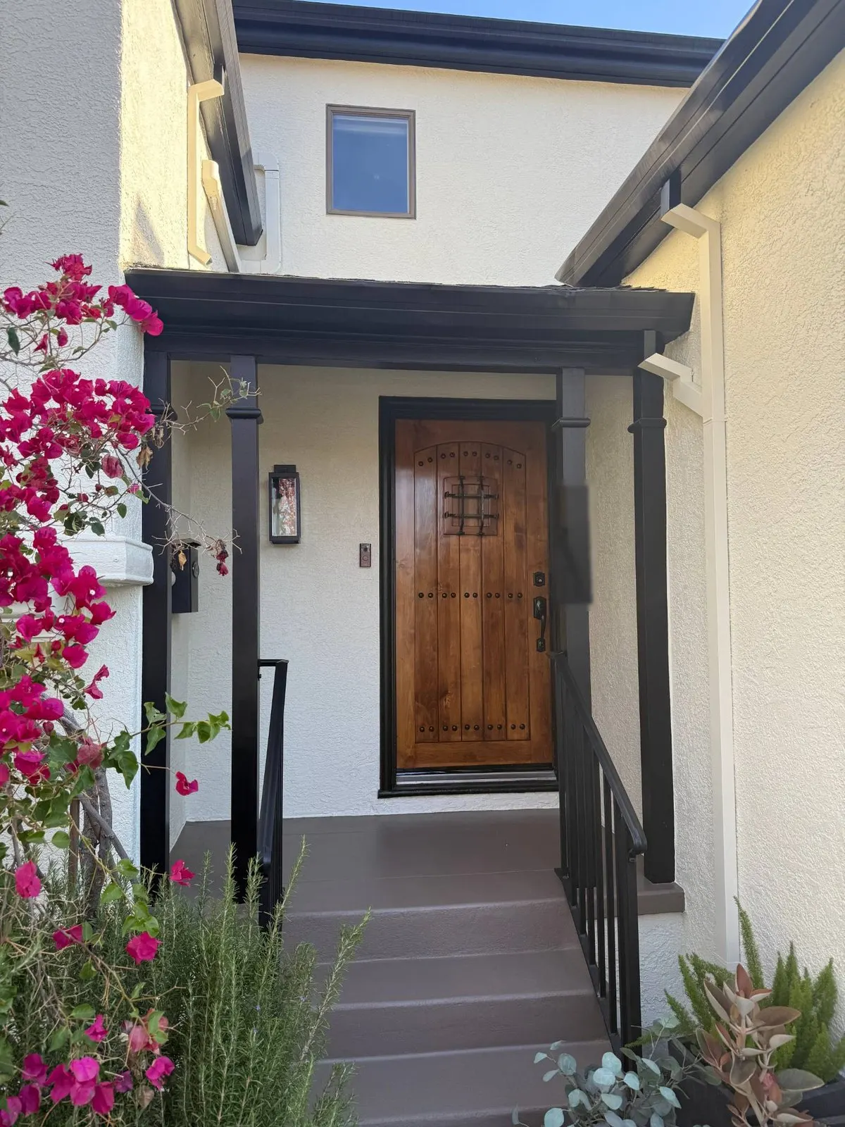 Front entry with white stucco, black posts and trim and coated steps