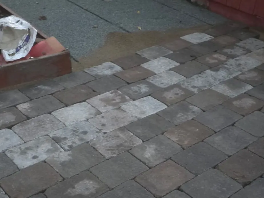 New pavers being laid onto a leveled bed next to a red shed